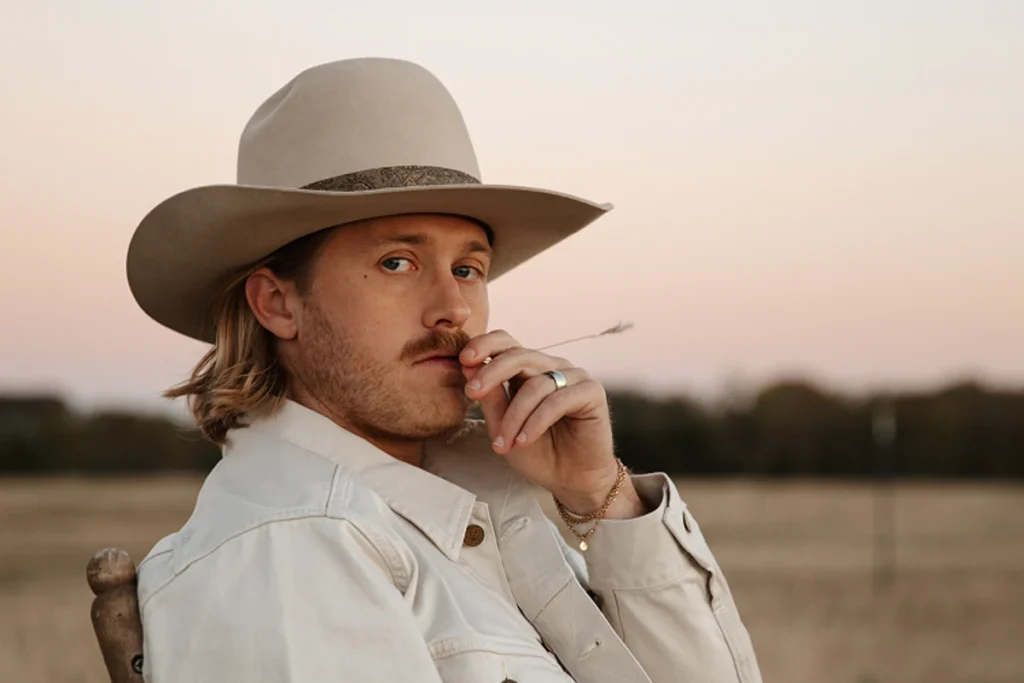 Corey Kent in a cowboy hat in a field at sunset