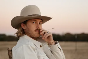 Corey Kent in a cowboy hat in a field at sunset