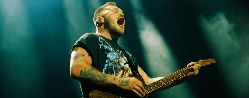 Zach Bryan playing guitar in the official 2027 Young Manhood and Other Donatable Organs Tour artwork